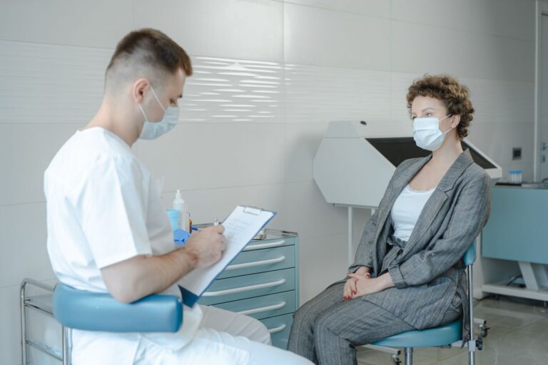 Doctor consulting a masked patient about rhinoplasty risks in clinic