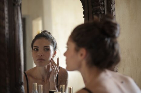 Woman checking her skin in a mirror during a skincare routine