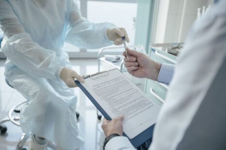Doctor handing a clipboard to a patient for signature during consultation