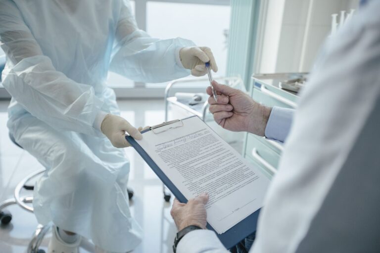 Doctor handing a clipboard to a patient for signature during consultation