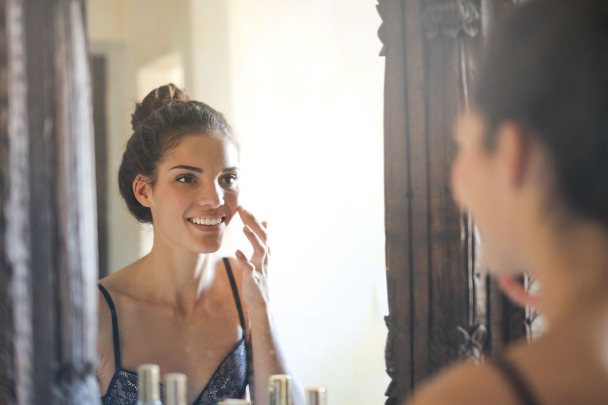 Smiling young woman looking at her reflection in a mirror